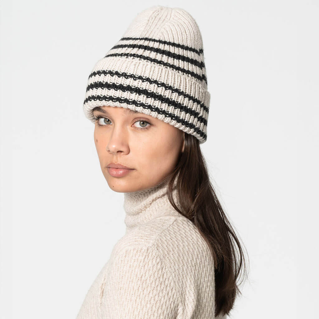 Woman wearing a striped beanie and light sweater on a white background