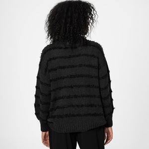 Person wearing a black textured sweater on a white background