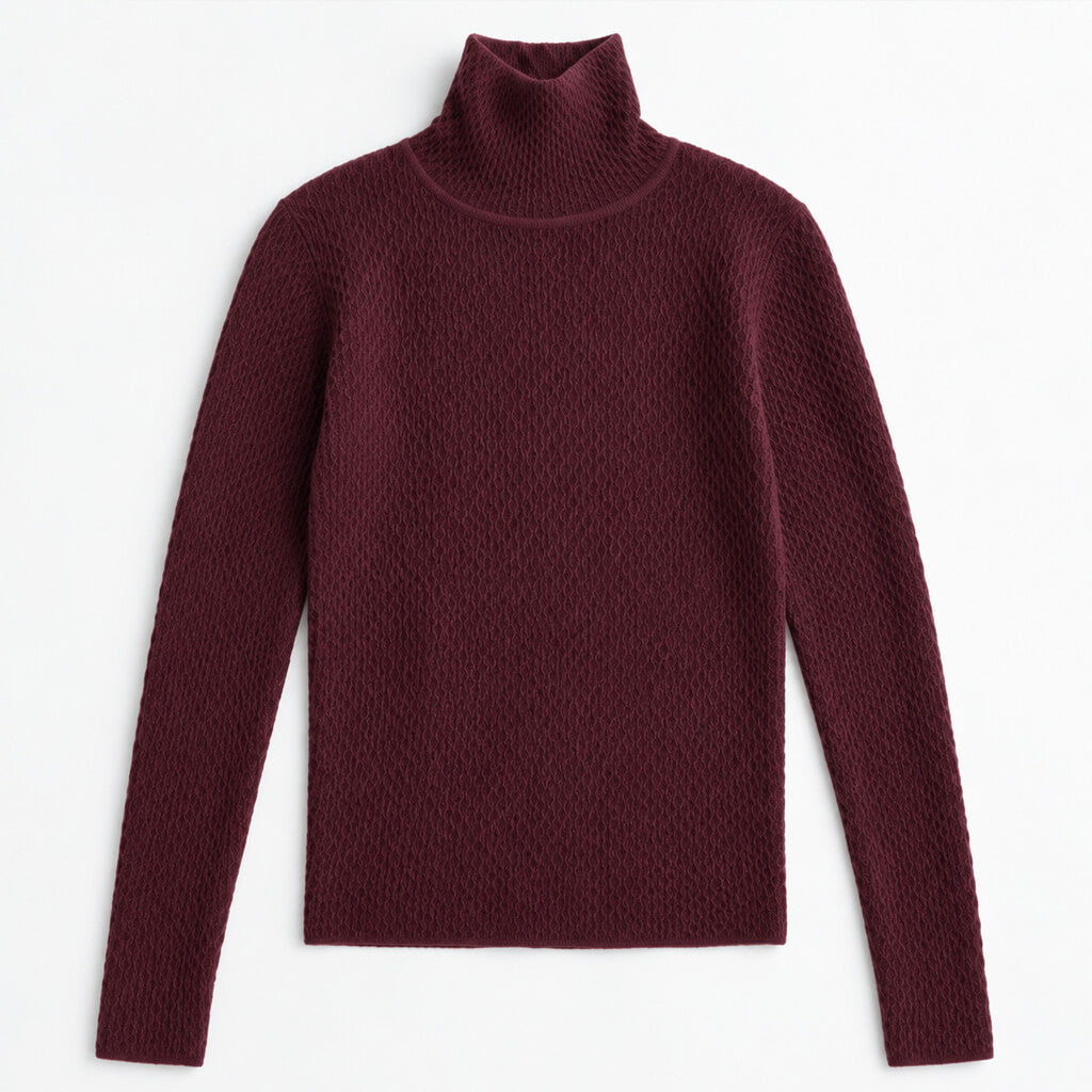 A woman wearing a dark burgundy ribbed turtleneck sweater and black skirt, posing against a solid beige studio background.
