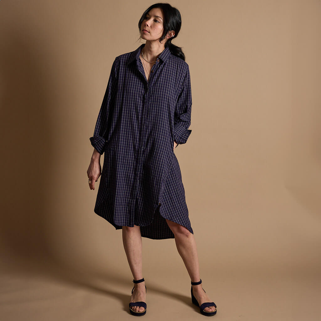 Woman wearing a blue checkered shirt dress made by Mulxiply.